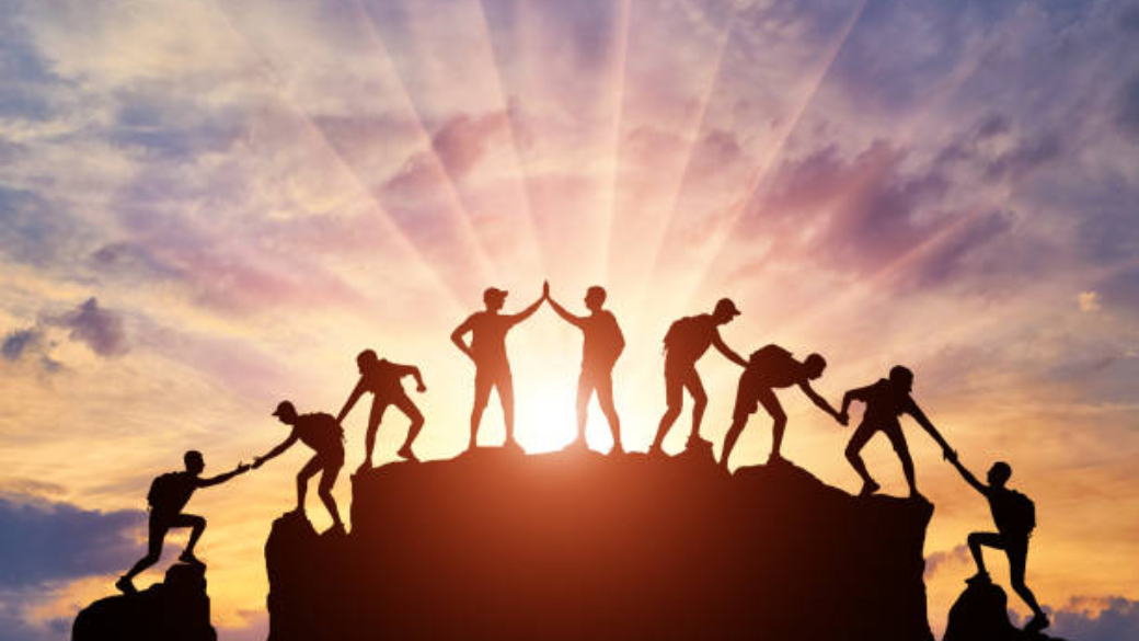 Silhouette of climbers who climbed to the top of the mountain thanks to mutual assistance and teamwork. Conceptual scene of a team of alpinists