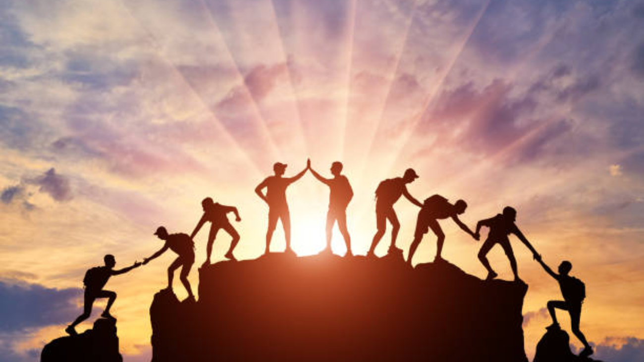Silhouette of climbers who climbed to the top of the mountain thanks to mutual assistance and teamwork. Conceptual scene of a team of alpinists