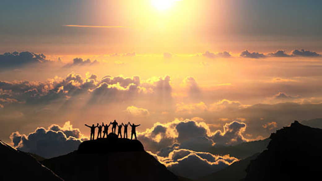A group of people standing on a hill over the beautiful cloudscape.